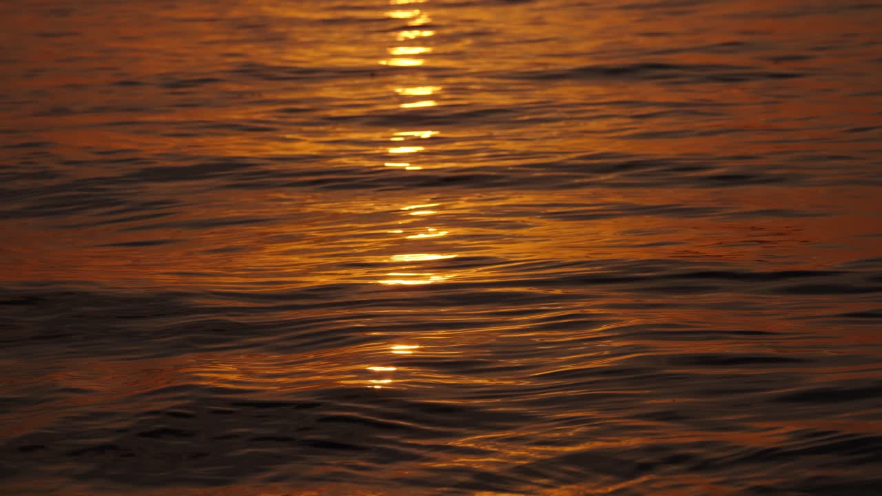 Close-up view of golden sunset reflections shimmering on ocean waves in Ko Tao, Thailand