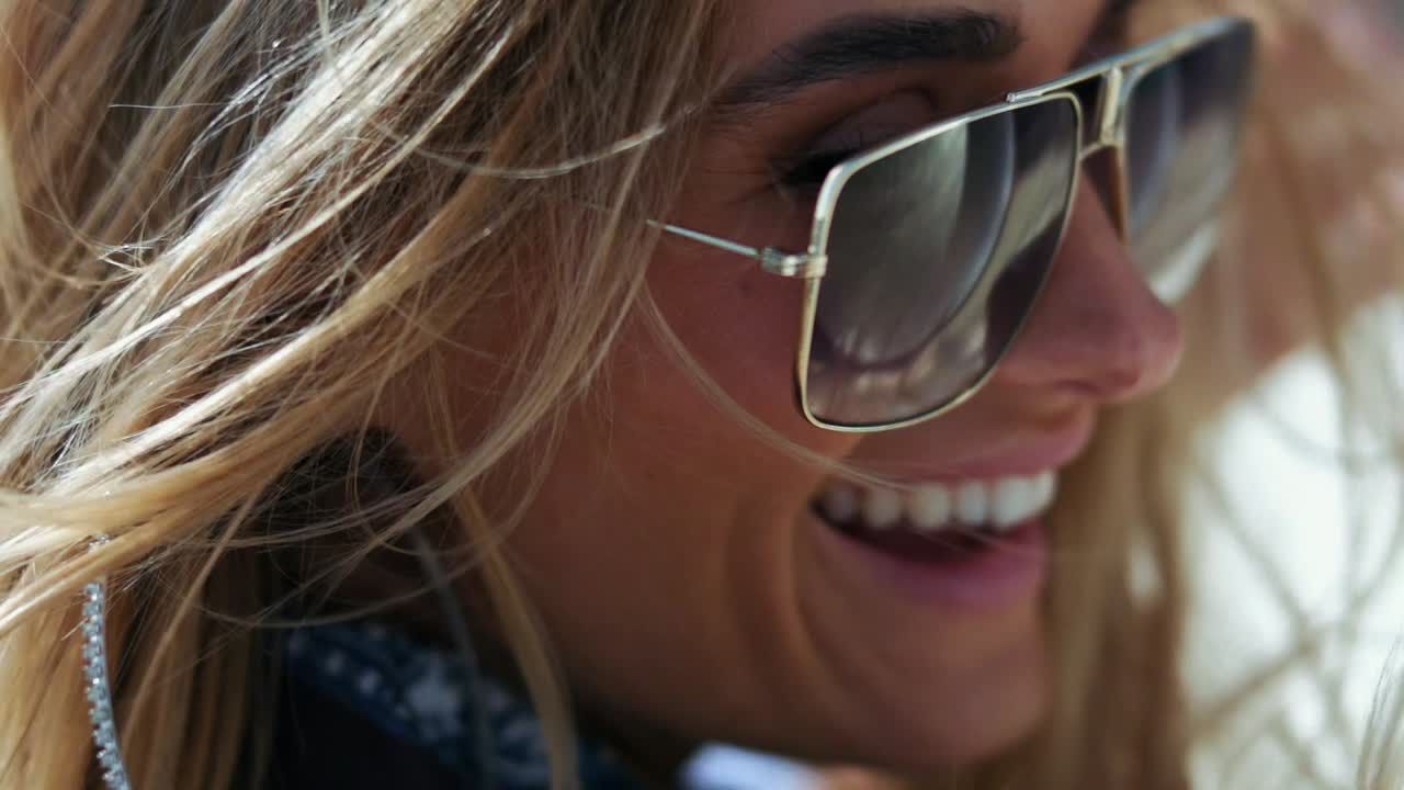 Close-up shot of blond woman in sunglasses laughing