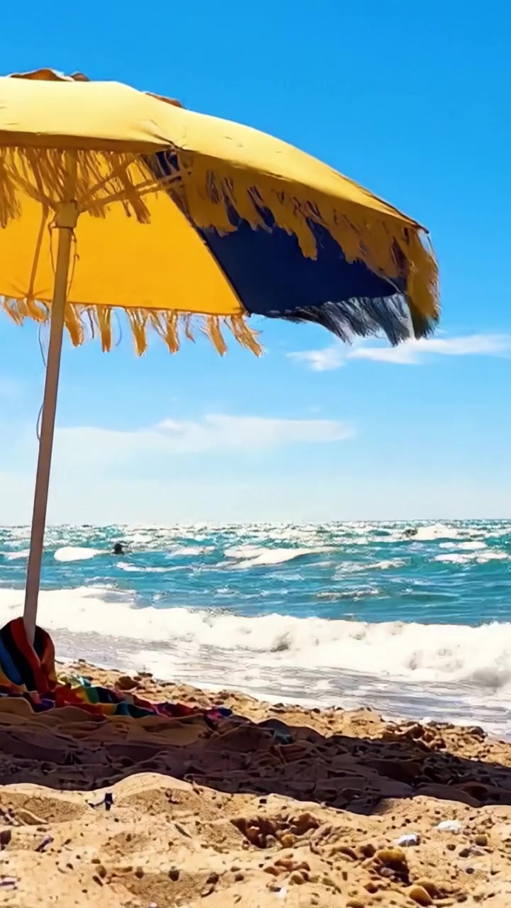 Una giornata rilassante in spiaggia con un ombrellone colorato e bellissime conchiglie sotto il cielo azzurro brillante e le onde scintillanti dell'oceano sullo sfondo