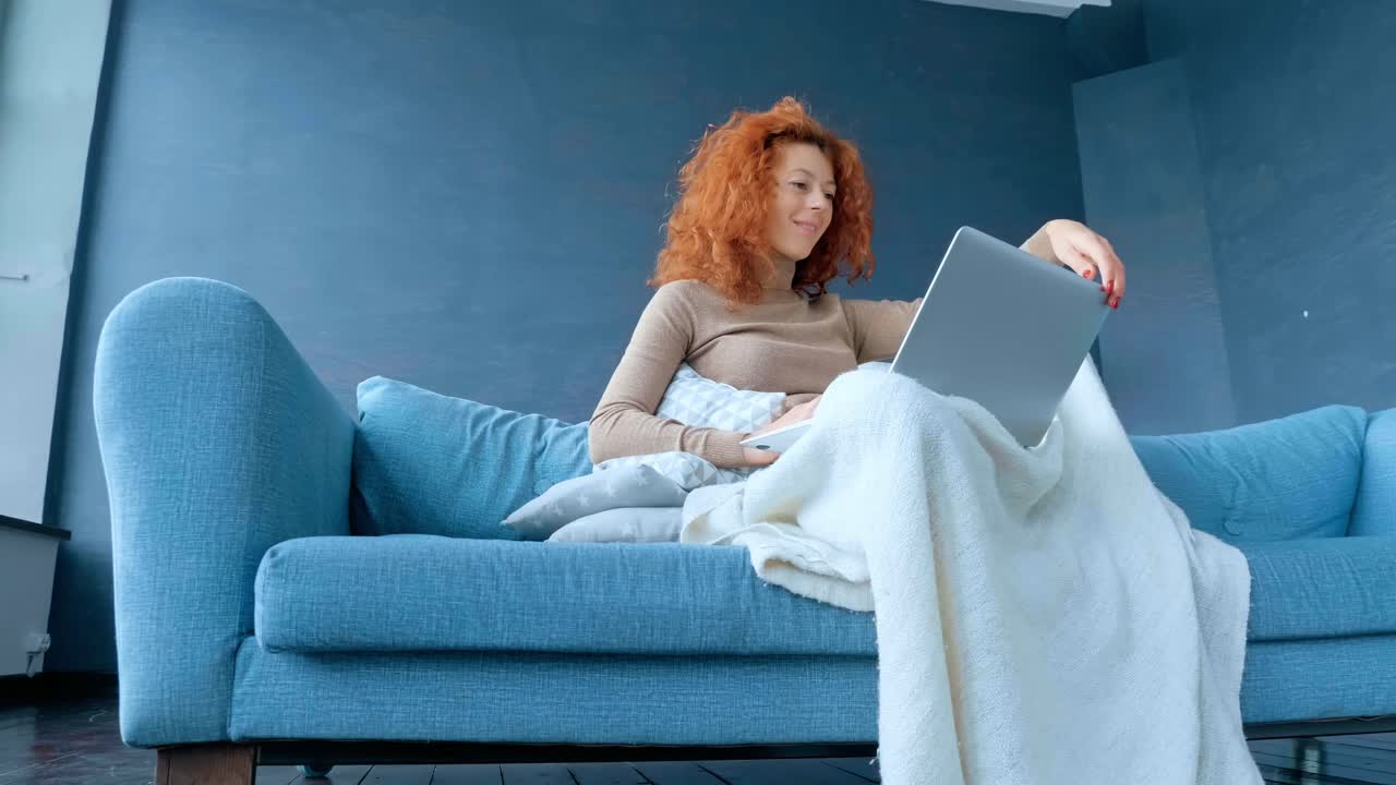 소파 에서 노트북 을 사용 하고 있는 여자