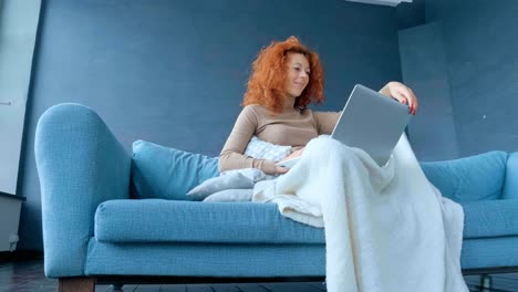 mujer trabajando en una computadora portátil en un sofá