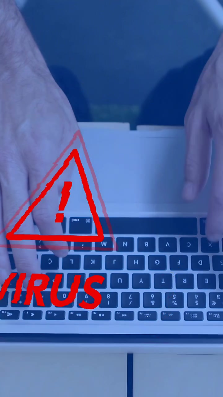 Vertical video: Man working on laptop in IT, causing red VIRUS alert glitching across hands, keys