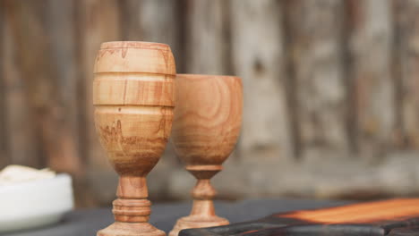 Carved-wooden-goblets-on-table-in-yard-against-fence