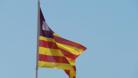 real fabric flag of balearic islands an autonomous community in spain, waving in the wind against a blue sky