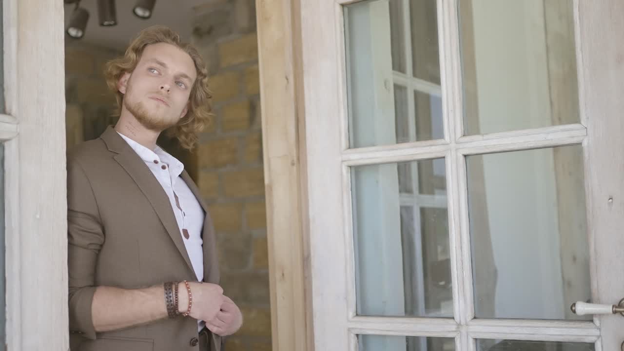 Man in a brown suit standing in front of a doorway