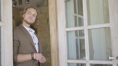 man in a brown suit standing in front of a doorway