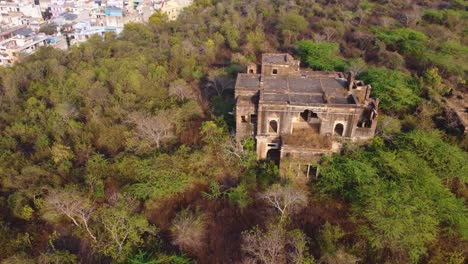 Drone shot of an abandoned ruins haunted building covered with forest in india
