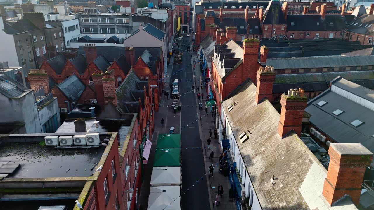 aerial cinematic drone shot going down the capital of Ireland, Dublin's famous Drury street. With bustling roads and streets filled with tourists and locals alike with seagulls flying past at sunrise