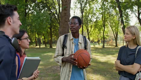 students talking in a park with a basketball