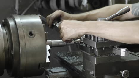 men's hands with a vernier caliper measuring the size of the details at work piece on lathe machine in the industrial factory. slow motion