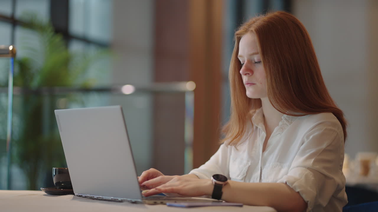 Pretty student woman using laptop in outdoors cafe while having cup of coffee. Cheerful woman working at cafe on laptop. Businesswoman working during layover at modern airport.