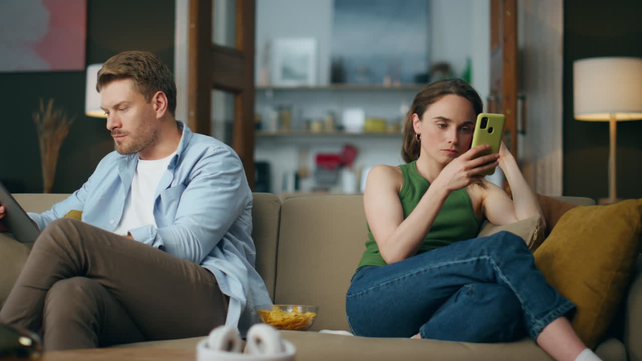 pareja adicta a internet con gadgets en el sofá en el hogar. fin de semana familiar contemporáneo