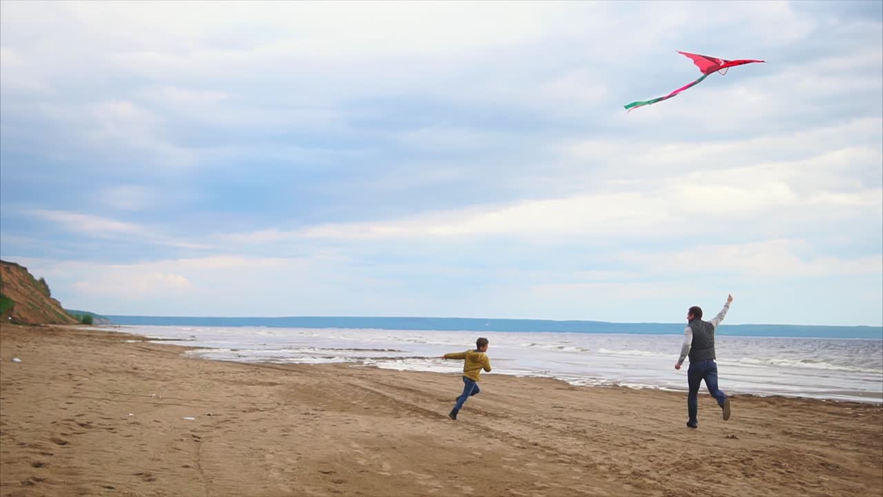 Father and son playing kite on the beach