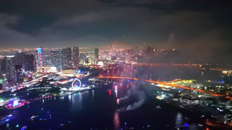 a drone hovers above a packed bay while fireworks thunder into the sky, captured in smooth cinematic motion