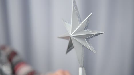 young happy woman decorating a christmas tree taking a silver star and hanging it on the top of the tree. shot in 4k