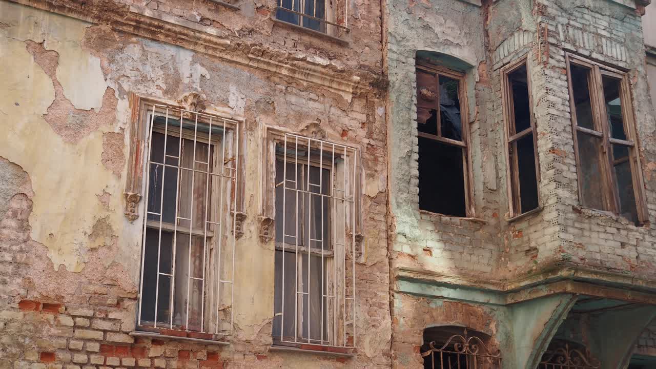 старое, заброшенное здание с сломанными окнами и рушащимся фасадом