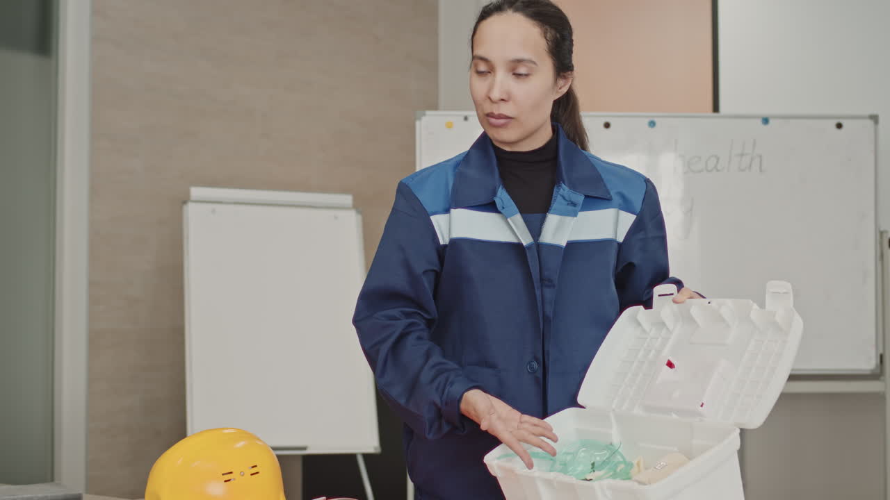Woman Showing Contents Of First Aid Kit At Industrial Facility