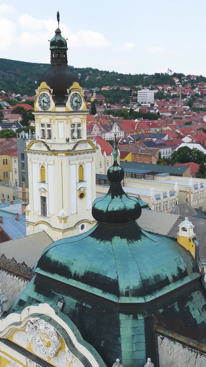 Splendida vista aerea del municipio di Pécs con un drone che orbita catturando sia la torre dell'orologio che la cupola decorata