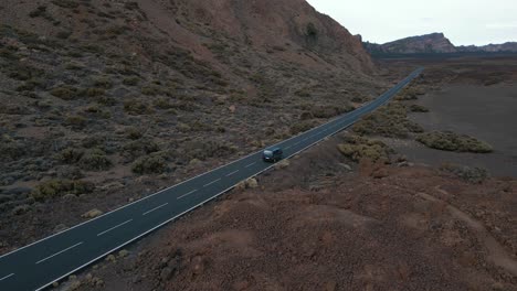 Breite-Luftfahrt-Eines-Blauen-Vans,-Der-Die-Autobahn-Hinunterfährt,-Mit-Einem-Großen-Berghang,-Teneriffa,-Spanien