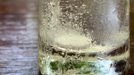 close up an effervescent tablet in a glass of water with space, warm tone lighting, real time footage.