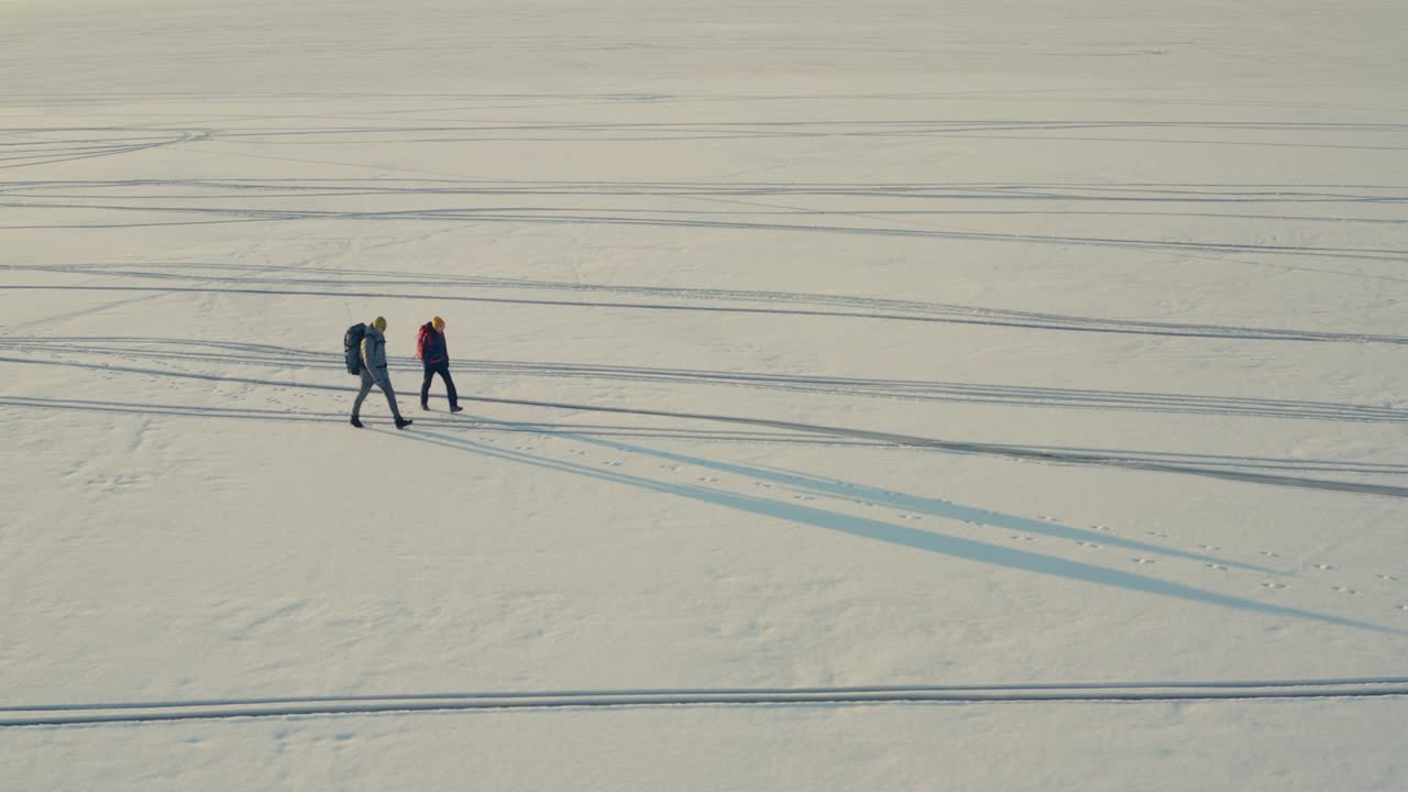 스노우 필드를 걸어가는 배을 가진 두 사람