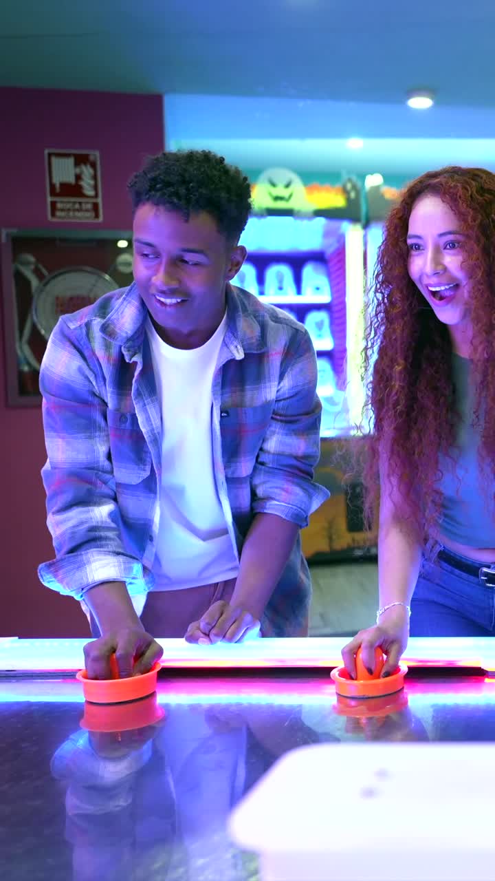 Amici che giocano a air hockey in una sala giochi