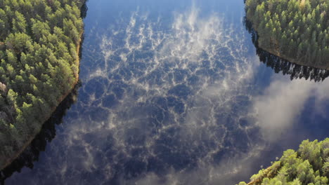 Drone-video-of-misty-calm-forest-lake-by-dawn,-Nice-contrast-with-clouds-reflecting-and-fog-on-the-lake-surface