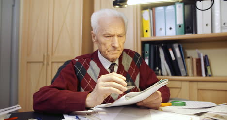 senior businessman reading contract with magnifying glass 1