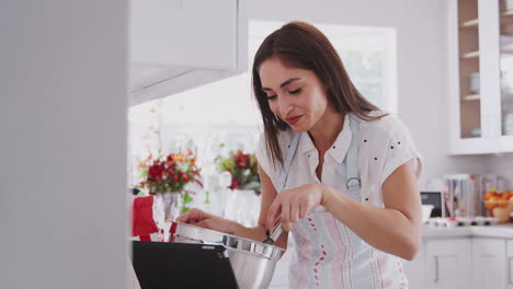mujer hispana milenaria preparando comida comprobando una receta en una tableta, de cerca, ángulo bajo