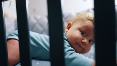 cute chubby face of a cute caucasian infant. close up. adorable baby lying in the crib on his belly.