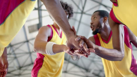 diverse basketball team huddles, showing unity with a group hand stack