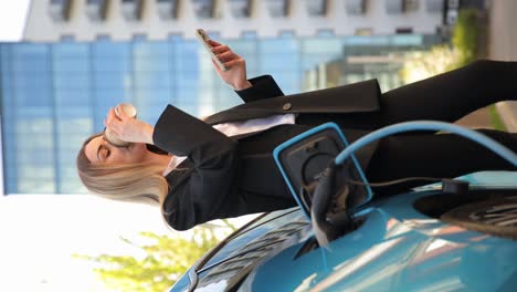 a beautiful girl drinks coffee and charges an electric car. business woman