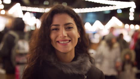 Retrato-De-Mujer-Sonriente-Disfrutando-Del-Mercado-Navideño-Por-La-Noche