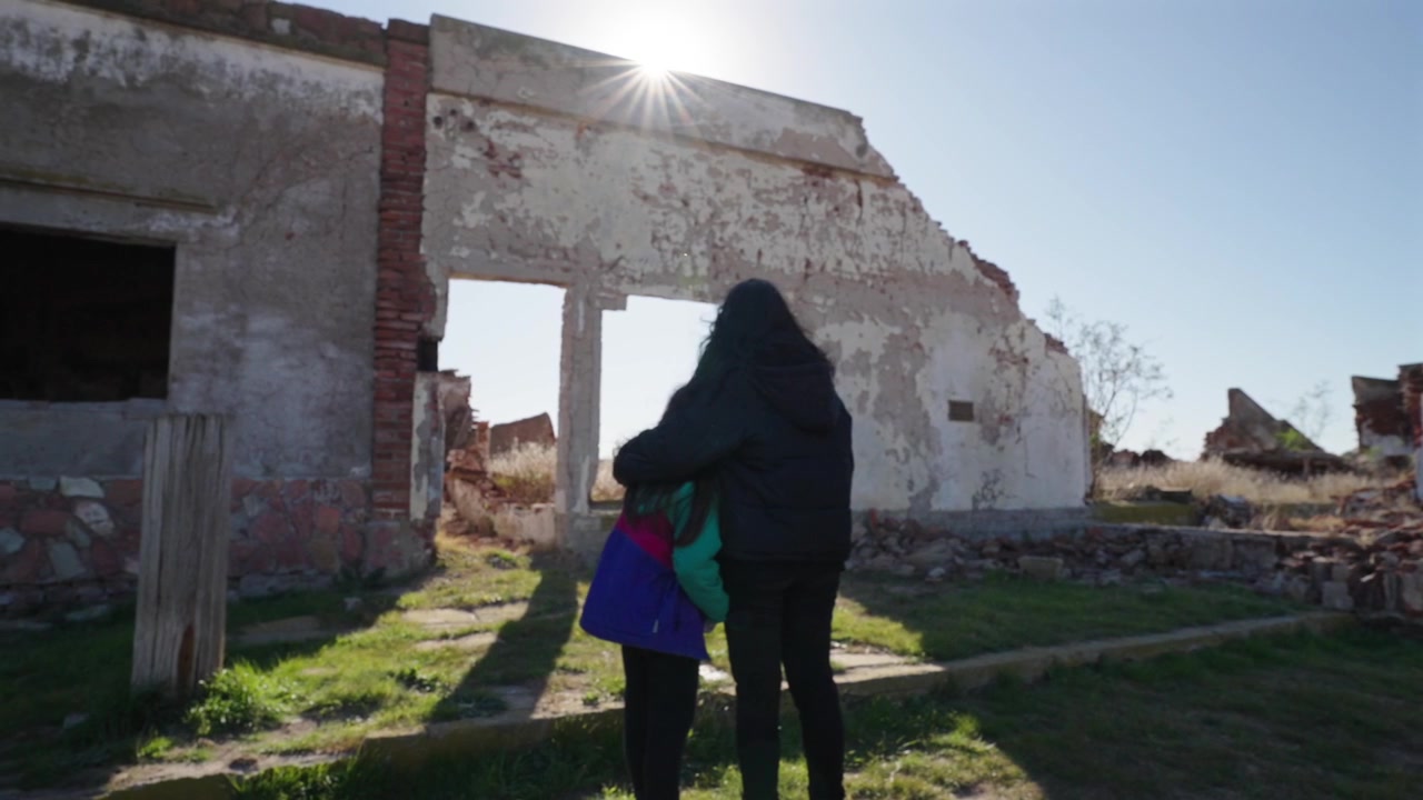 Un momento toccante: madre e figlia si abbracciano mentre osservano le rovine di mattoni distrutte e abbandonate della città fantasma allagata di Villa Epecuén in Argentina.