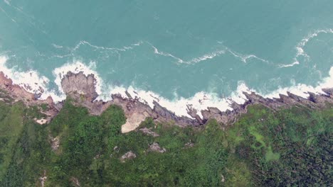 Aerial-view-of-a-jagged-rock-island,-surrounded-with-lush-green-nature-and-Hong-Kong-bay-water