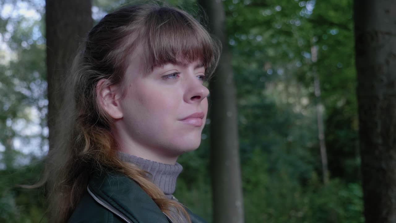 mujer joven en madera sombreada sonríe y se relaja en la brisa, primer plano