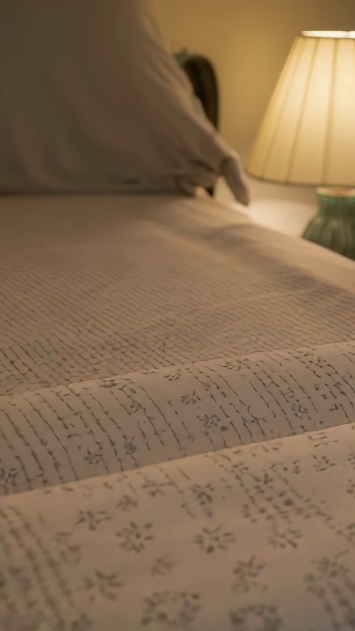 Adult stirring awake, sitting up on bed and smoothing bedspread, animated lamp rays guiding sleep