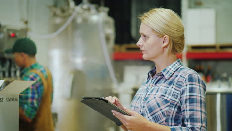 worker working with a tablet on the background of the conveyor in the background beverage industry