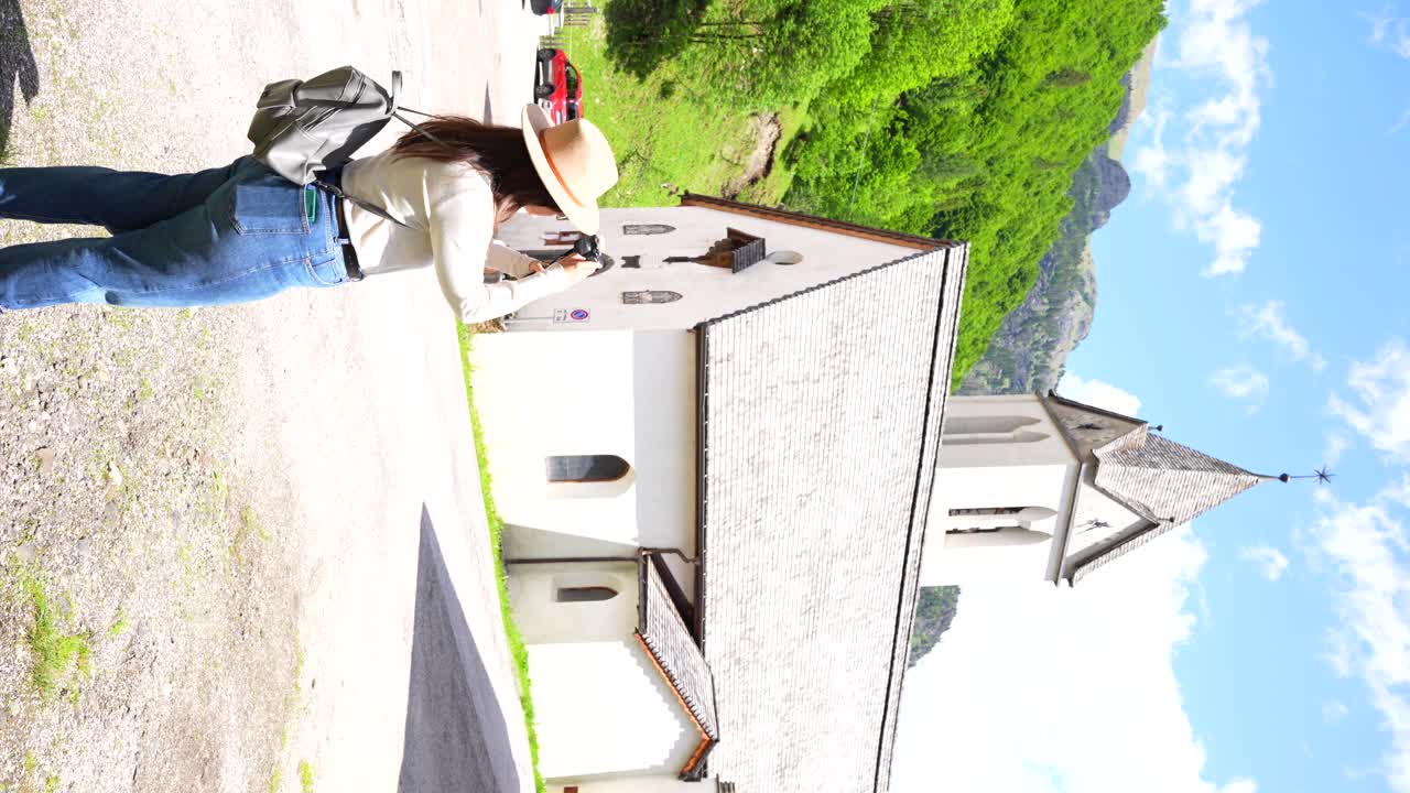 una mujer turista filma una iglesia en sottoguda, italia.