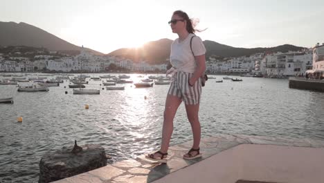 Young-woman-walking-by-the-sea-at-golden-hour-and-turn-back-to-watch-the-sunset