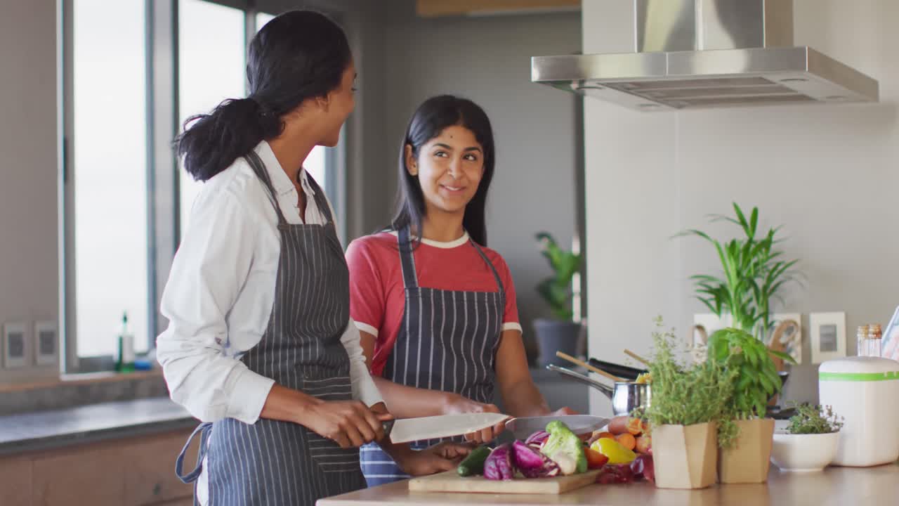 video de felices amigas diversas cortando verduras y preparando comida