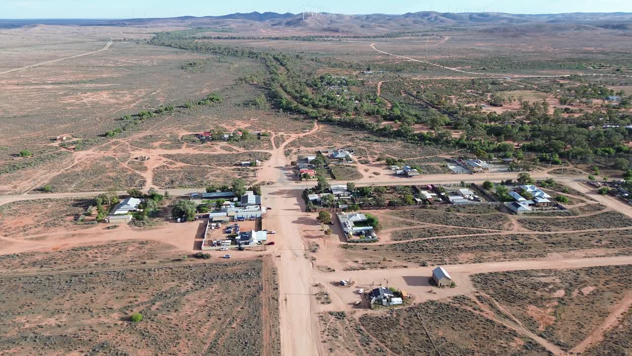 las imágenes de drones se deslizan sobre una pista de tierra en silverton, en el interior de australia, capturando paisajes de tierra roja, terrenos escarpados y horizontes interminables en una escena de belleza remota y atemporal.