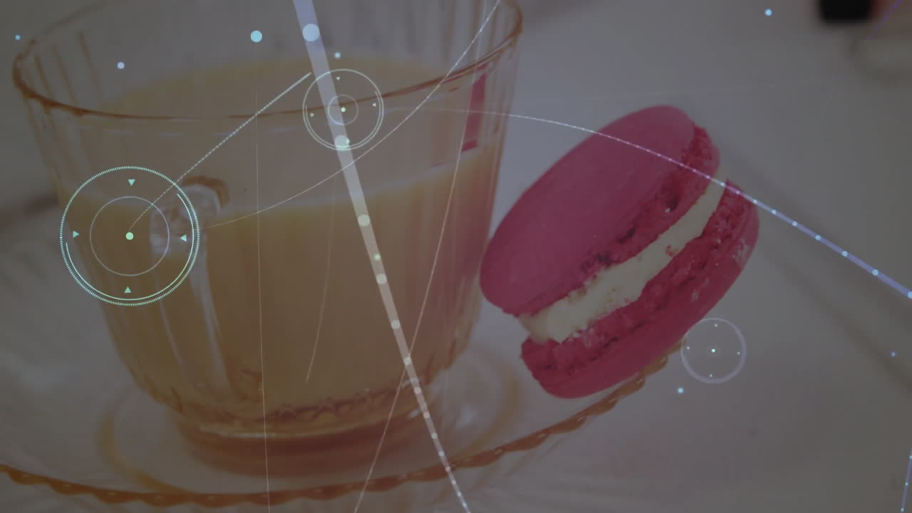 Glass teacup holding light brown beverage being visualized, with pink macaron, digital overlay