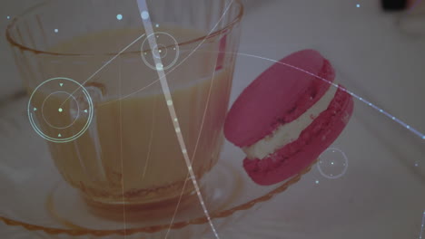 glass teacup holding light brown beverage being visualized, with pink macaron, digital overlay