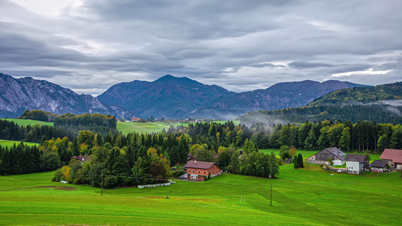 Nebbia e nuvole minacciose si muovono sul rigoglioso paesaggio rurale del villaggio di Attersee, time-lapse.