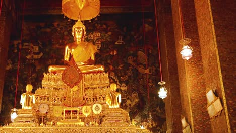 a golden buddha statue sits majestically surrounded by intricate temple decorations and hanging lanterns.