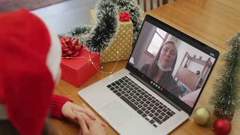 Mujer-Caucásica-Feliz-En-Videollamada-Con-Madre-Mayor-Con-Mascarilla-En-Navidad