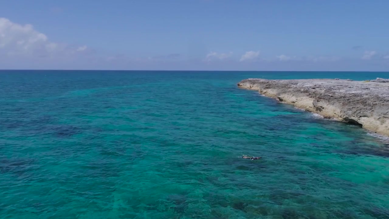 Vista aerea con drone di un'isola deserta delle Bahamas con barca a vela solitaria e snorkelisti