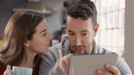 Happy-couple-using-digital-tablet-at-home-spending-time-together