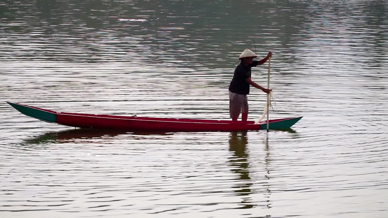 pescador desconocido que busca pescado usando un barco tradicional y una red